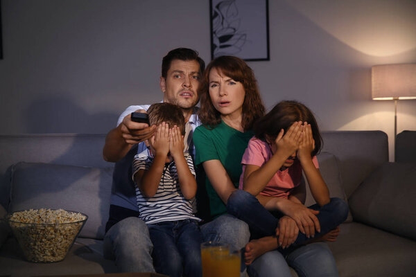 Family watching TV in room at evening time