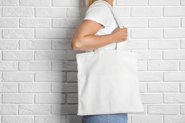 女人用手提包包在砖墙附近 模拟设计 — 图库照片