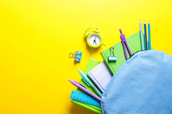 颜色背景下的背包和学校文具的平躺组合 — 图库照片