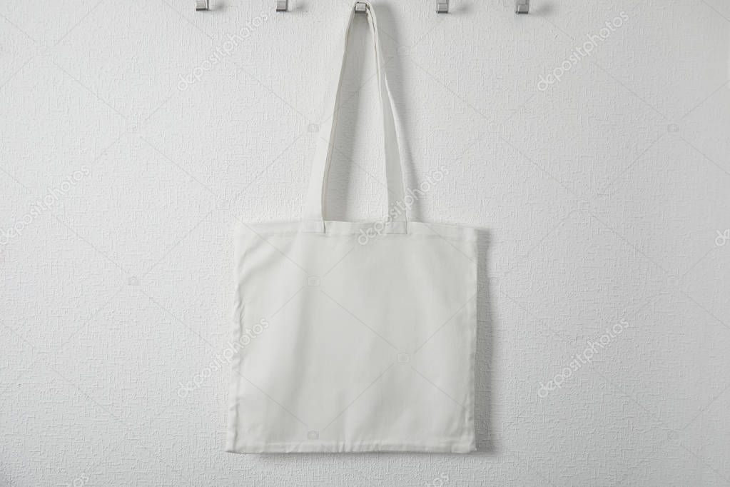 Tote bag hanging on white wall. Mock up for design