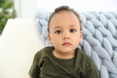 Kanepede şık giysiler içinde şirin Afrikalı-Amerikalı bebek