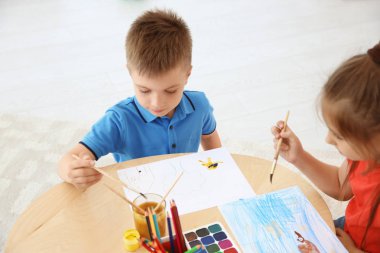 Sevimli küçük çocuklar oda oynarken masada boyama