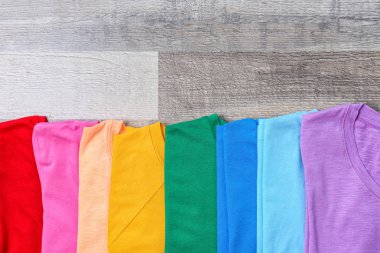 Ahşap arka plan üzerinde renkli koleksiyon t-shirtler