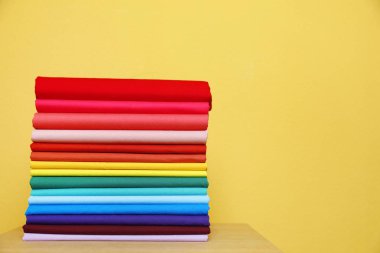 Tablo renkli arka plan üzerinde parlak t-shirt yığını