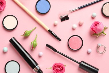 Pastel pembe arka planda dekoratif makyaj ürünleri ile düz konum