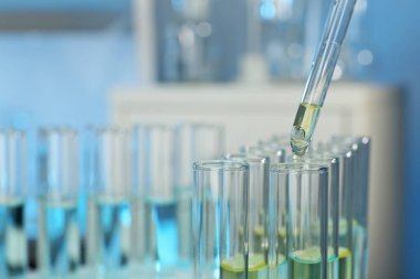 Laboratuvarda numuneyle test tüpüne damlatılıyor, yakın plan. Kimyasal analiz.