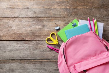Sırt çantası, okul kırtasiye ve ahşap arka plan üzerinde metin için yer düz yatıyordu kompozisyonu