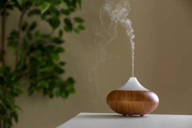 Aroma oil diffuser lamp on table against blurred background clipart