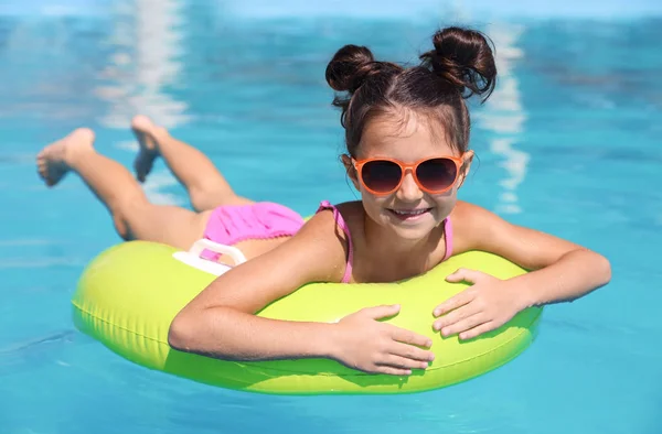 Little girl with inflatable ring in swimming pool