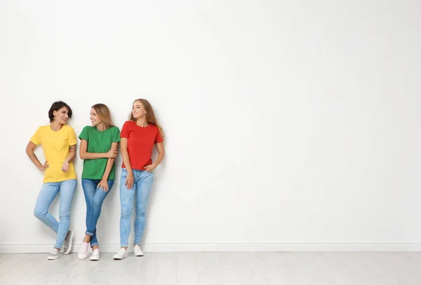 ジーンズと光壁の近くのカラフルな シャツの若い女性のグループ — ストック写真