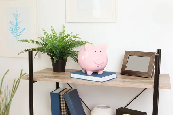 Shelving unit with decorative interior elements and piggy bank near white wall