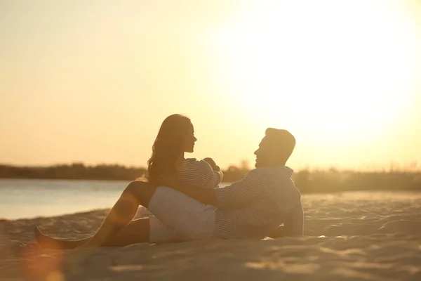 夕暮れ時のビーチで一緒に休んで幸せな若いカップル — ストック写真