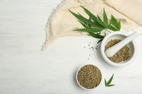 Flat lay composition with hemp seeds and space for text on wooden background