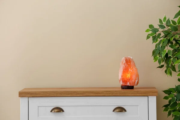 Himalayan salt lamp on cabinet against light wall