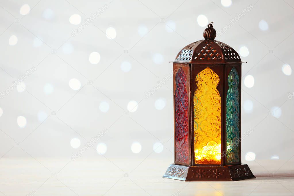 Muslim lamp Fanus and space for design on blurred lights background