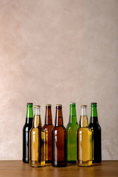 Flaschen Mit Unterschiedlichem Bier Auf Dem Tisch Vor Farbigem Hintergrund — Stockfoto