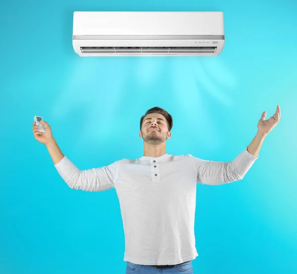 Young Man Operating Air Conditioner Color Background — Stock Photo, Image