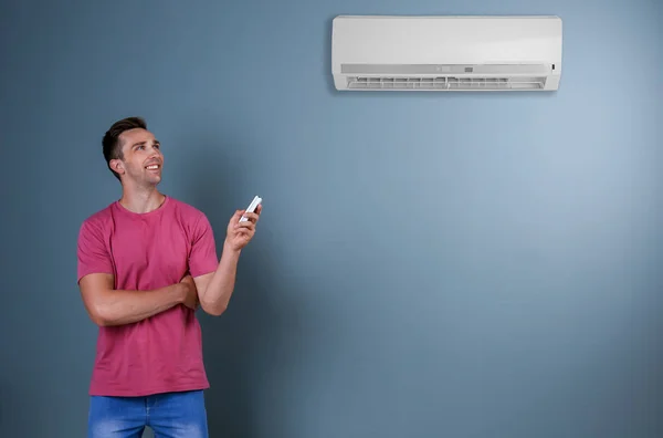 Jeune Homme Opérant Climatiseur Sur Fond Couleur — Photo