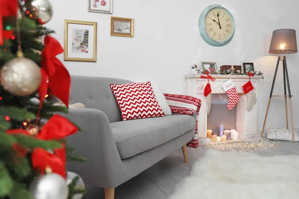 Comfortable sofa near decorated Christmas tree and fireplace in living room