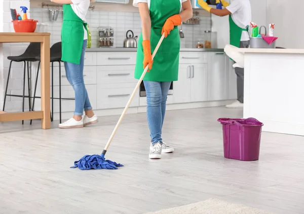 Woman cleaning floor with mop in kitchen, closeup