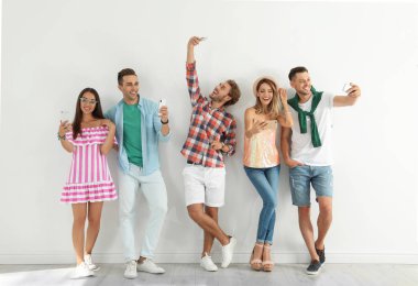 Bir grup genç insan selfie beyaz duvarının yakınında alarak