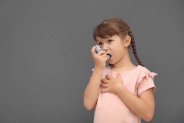 Astım inhaler gri arka plan üzerinde küçük kızla