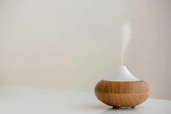 Aroma oil diffuser lamp on table against light background