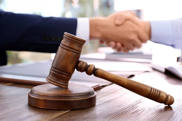 Gavel and blurred lawyer handshaking with client on background