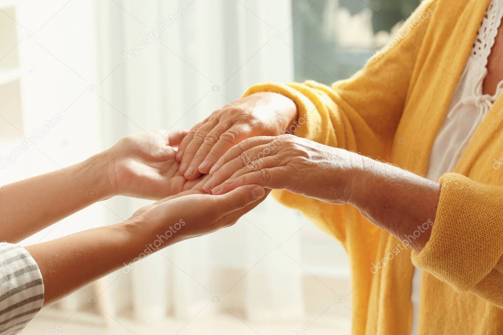 Helping hands on blurred background, closeup. Elderly care concept