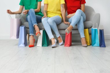 Grup alışveriş torbaları Divan ışık duvarının yakınında oturan olan genç kadın