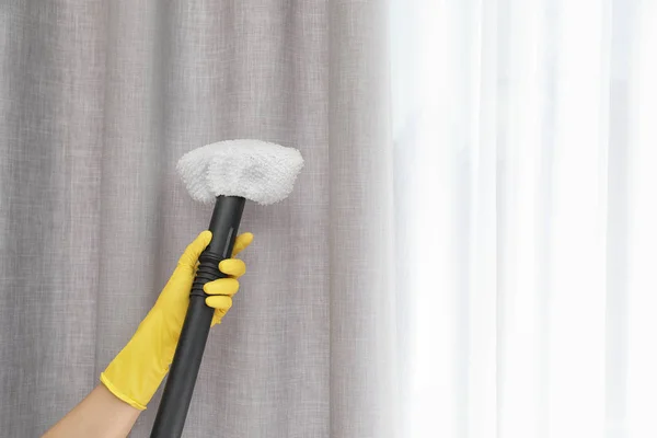 Janitor removing dust from curtain with steam cleaner indoors, closeup