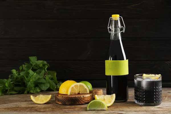 瓶和玻璃与自然木炭柠檬水在桌反对黑暗的背景 — 图库照片