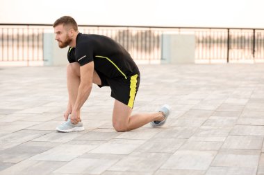 Açık havada güneşli günde çalıştırmadan önce bağlama ayakkabı bağcığı genç adam
