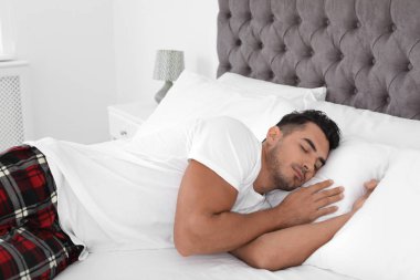Yumuşak yastık ile evde yatakta uyuyan genç adam