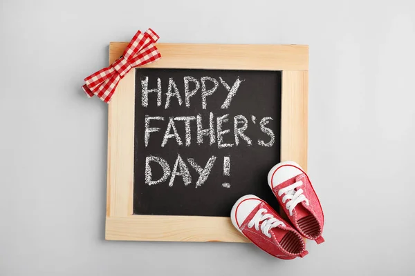 灰色の背景に黒板と赤ちゃん靴フラット横たわっていた成分 ハッピー父の日 — ストック写真