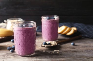 Ahşap masa üzerinde yaban mersini smoothies ile kavanoz