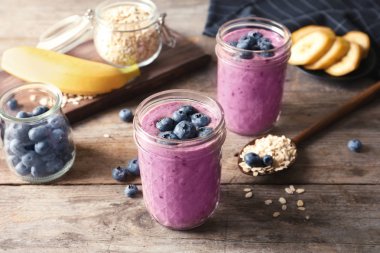Ahşap masa üzerinde yaban mersini smoothies ile kavanoz