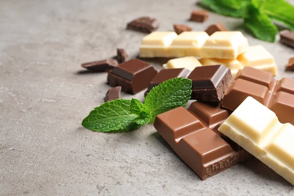 Different kinds of chocolate with mint on gray table