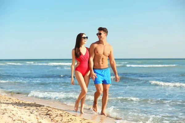 幸せな若いカップル一緒にビーチで歩く — ストック写真