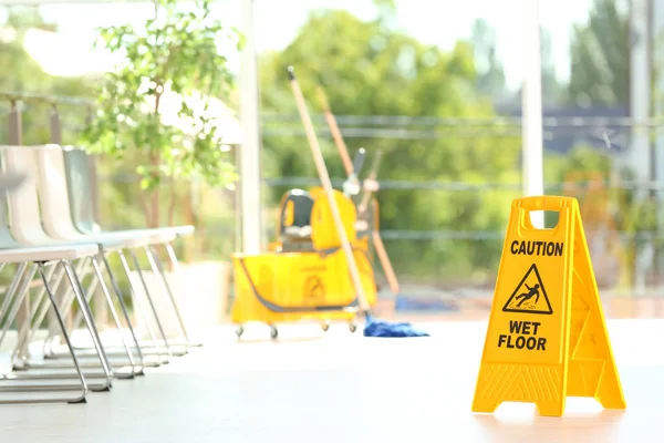 安全标志与词组警告湿地板和模糊拖把桶在背景 清洁服务 — 图库照片