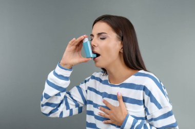 Astım inhaler renk arka plan üzerinde kullanan genç kadın