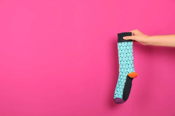 Woman holding bright sock and space for design on color background