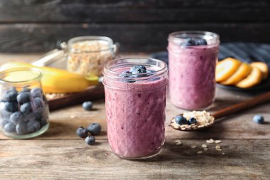 Ahşap masa üzerinde yaban mersini smoothies ile kavanoz