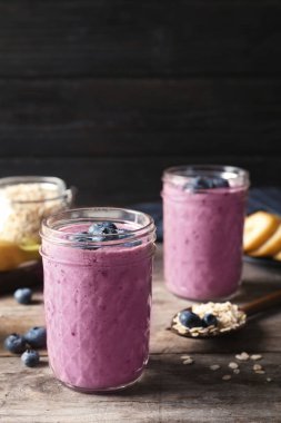 Ahşap masa üzerinde yaban mersini smoothies ile kavanoz