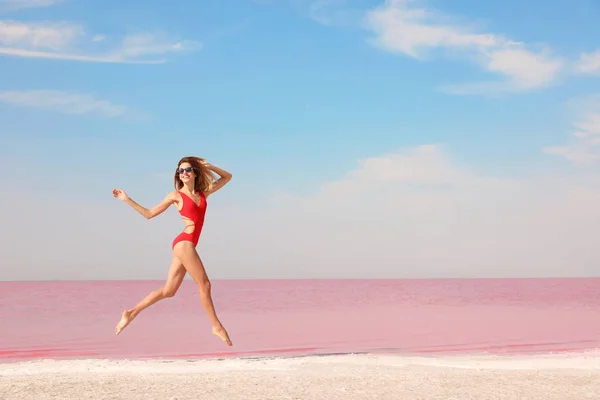 Красивая Женщина Купальнике Прыгает Возле Розового Озера Солнечный День — стоковое фото
