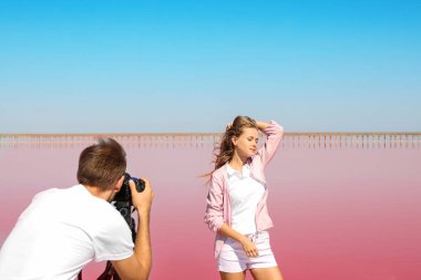 Profesyonel fotoğrafçı alarak güneşli pembe lake yakınındaki kadın fotoğrafı