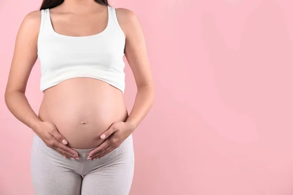 Młoda Kobieta Ciąży Trzymając Się Ręce Brzuchu Przed Kolor Tła — Zdjęcie stockowe