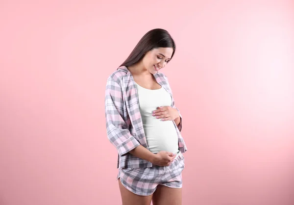 美丽的孕妇手抱在腹部对颜色背景 — 图库照片