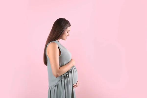 美しい妊娠中の女性は 色の背景に対して腹に手を繋いでいます テキストのためのスペース — ストック写真