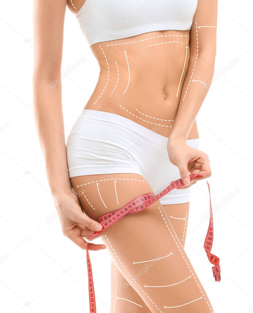 Young woman with marks for liposuction operation and measuring tape on white background. Cosmetic surgery